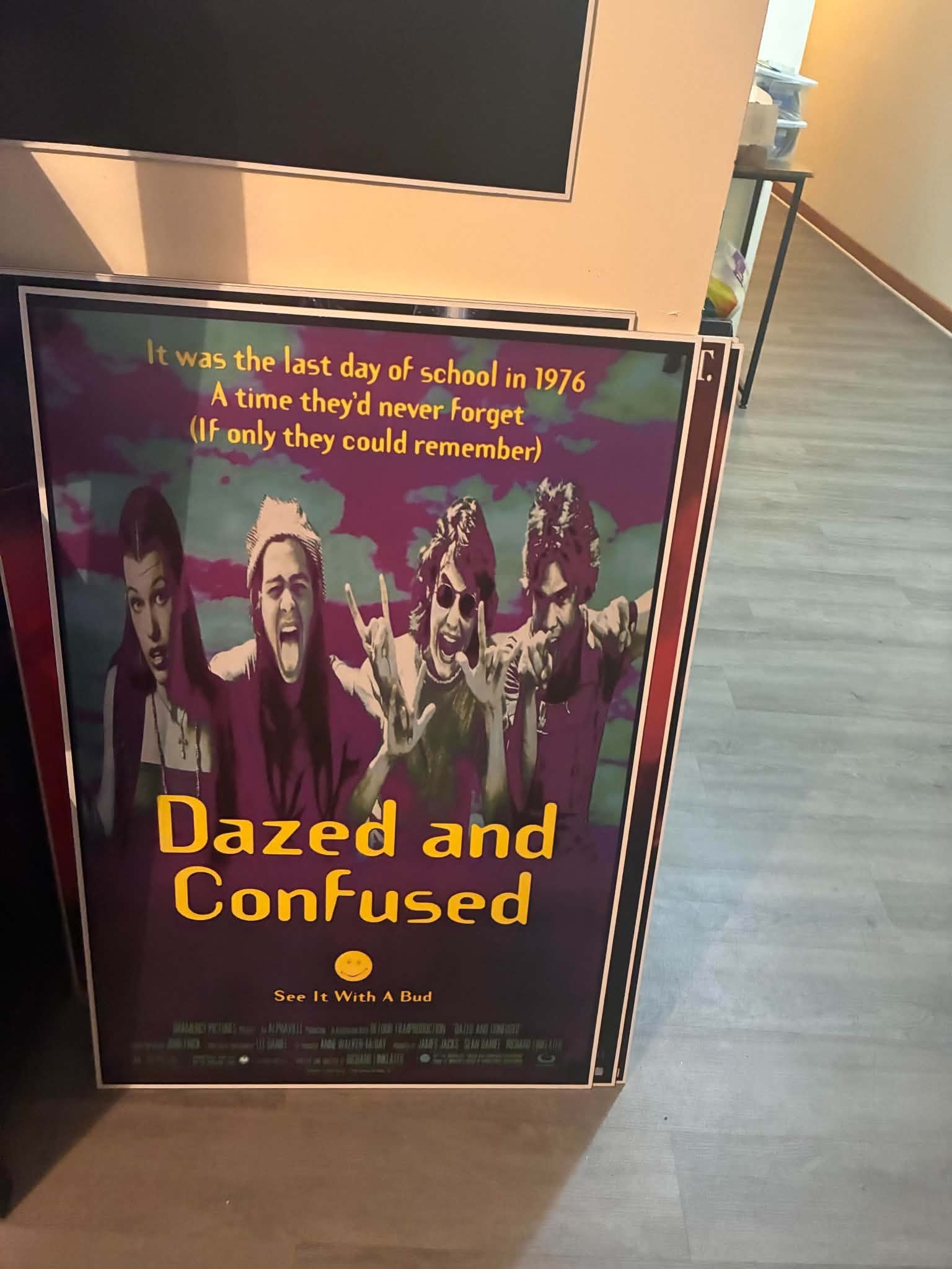 Photo of a Dazed and Confused poster print of the four leads in purple and green concert-style photography