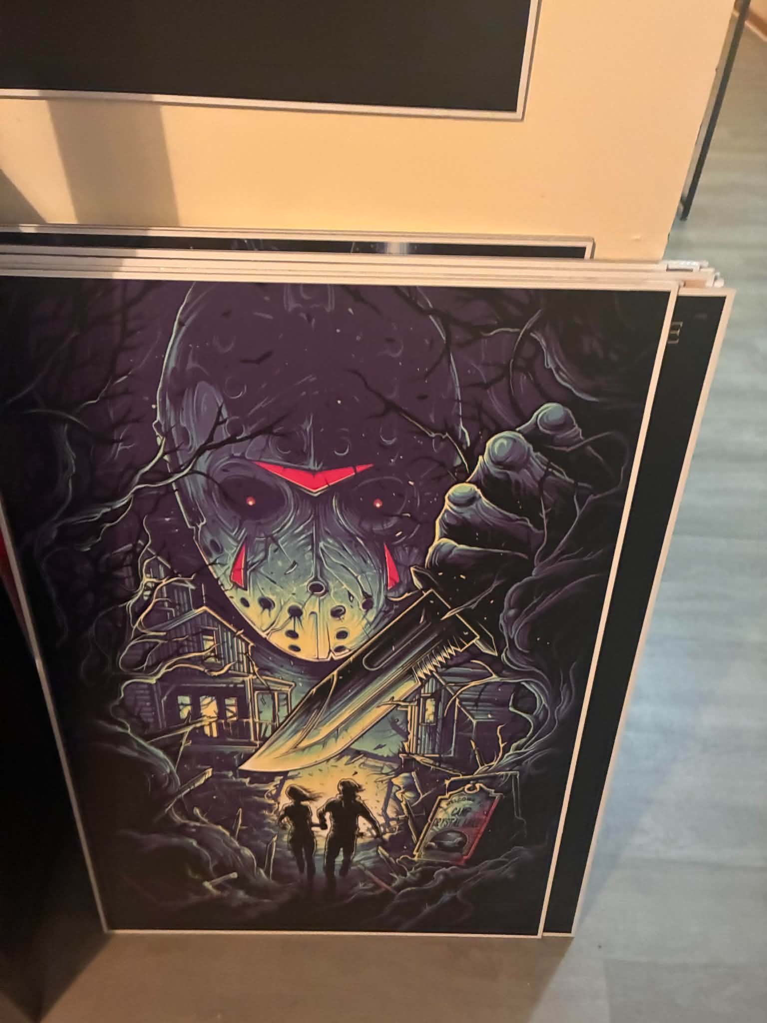 Photo of a limited-edition Friday the 13th art print with Jason Voorhees' hockey mask looming from twisted purple night woods over Camp Crystal Lake